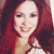 Pixelated portrait of a person with long red hair, light skin, and a neutral expression wearing a light-colored top.