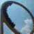 A pixelated circular frame with a dark brown border and light blue interior showing faint cloud-like patterns.