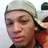 Pixelated close-up of a person wearing light-colored headwear and dark clothing, with visible facial features including eyes, nose, mouth, and skin texture.
