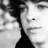 Black-and-white pixelated image of a person's face in profile, showing dark hair and a smooth jawline against light background.