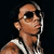 Pixelated image of a person wearing sunglasses and earphones, with a sleeveless striped shirt against dark background.
