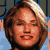 Pixelated static image of a person with brown hair and light skin, wearing red lipstick, against a blue and gray background.