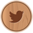 Circular wooden icon with brown Twitter bird silhouette centered on light brown wood grain background.
