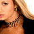 A woman with blonde hair and a black choker necklace appears in two showing different poses