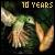 Pixelated image with '10 YEARS' text at top, green and beige figure holding a golden object against dark background.