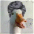 Pixelated static image of a duck-like character with dark gray curly hair, white face, and brown beak against light background.