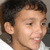 Pixelated close-up of a person's face with short dark hair, visible ear, and light skin tone against a neutral background.