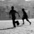 Silhouetted figures of two people running on a field with one figure kicking a ball, displayed in four