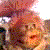 Pixelated static image showing a figure with light brown hair and a pinkish background with scattered red and purple elements.