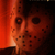 Pixelated static image of a red mask with dark eye and mouth openings, set against a gradient background transitioning from bright orange to black.