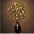 A pixelated static image shows a dark bottle with a light-colored neck and cap, topped by a cluster of golden-yellow square pixels resembling sparkles or bubbles against a brown background.