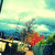 Pixelated landscape with blue sky, white clouds, green trees, and red foliage on a path with yellow structures.