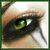 Static close-up of a single green eye with black eyeliner and brown skin tones, framed by dark hair strands against a light background.