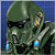 Pixelated green armored figure with dark visor, yellow earpiece, and blue lights on chest and shoulder against blue background.