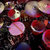 Pixelated image of multiple overlapping circular shapes in red, pink, and white tones against a dark background with scattered light patches.