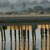 A pixelated image shows a bridge with vertical supports and a cityscape background under a gray sky.