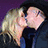 Two pixelated figures in a close embrace, one with light hair and the other with dark hair, against a dark purple background.