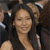 A pixelated static image shows a person with long dark hair wearing a dark sleeveless top, with a blurred background containing indistinct shapes and colors.