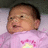 Pixelated image of a child in a pink outfit with a yellow and pink design, dark hair, and a light background.