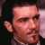 Pixelated static image of a person's face with visible facial features and partial ear, rendered in low-resolution style against dark background.