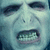 A pixelated image of a pale face with visible teeth, accompanied by red text on black and gray backgrounds.
