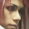 A close-up of a person with light skin and reddish-brown hair, showing a side profile with a neutral expression and a pink heart symbol in the bottom right corner.