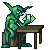 Green pixelated goblin-like figure with pointed ears sits at brown table, holding a white object near its face against gray background.