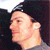 Pixelated profile view of a person with dark hair wearing a dark top against a dark background with light sky visible.