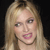Static pixelated image of a person with long light brown hair, pink lips, and visible teeth against a dark background.