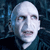 Pixelated close-up of a bald figure with pale skin, dark eyes, and a neutral mouth against a dark blue pixelated background.