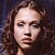 Pixelated portrait of a person with long brown hair against dark background, static image.
