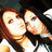 Two pixelated faces in close proximity, one with brown hair and the other with dark hair, both wearing white tops against a dark background.