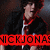 Pixelated image of a person with dark hair wearing a black jacket over red clothing, standing against a dark background with a bright red banner displaying partial text.