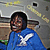 A person in a blue hoodie with a white eagle emblem smiles broadly, seated against a gray background with yellow text elements.