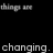 Black background with repeated white text 'things are' and 'changing.' in pixelated font, arranged in a pattern