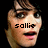 Pixelated image of a person with short dark hair and light skin, showing text overlays across the face in a