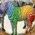 Rainbow-colored horse with white legs and black hooves stands on brown ground, head turned left to right across frames.