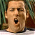 Pixelated close-up of a bald man's face with closed eyes and an open mouth, set against a blurred green and brown background.