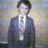 Two side-by-side pixelated figures in dark suits with white collars, one with red squares over eyes, against a blurred background.