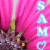 Static 50x50 pixel icon with pink background featuring vertical blue text "S A M O" and a blurred floral or abstract shape on the left side.
