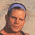 Pixelated static icon of a person with short brown hair wearing a blue headband, set against a beige background.
