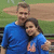 Two people in blue shirts embrace in a pixelated outdoor scene with green and brown background elements.