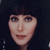 Pixelated close-up of a person's face with dark hair against a dark background, showing eyes, nose, mouth, and neck in a static image.