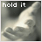 A 48x48 pixel animated buddy icon showing a grayscale close-up of hands holding, with text "hold it" at the top and a small heart symbol in the bottom-right corner of one frame.