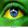 A close-up of a human eye with green eyelids and yellow-orange iris, featuring the Brazilian flag's blue star and white band in the pupil area.