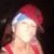 A person wearing a red cap with blue trim and red sleeveless top, shown in three with slight head movement against a dark background