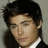 Pixelated image of a person with dark hair and a white-collared shirt on a pink background with pixelated text.