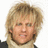 Pixelated close-up of a person with light brown hair, wearing dark clothing against a white background.