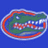 Green alligator head with white teeth and red accents inside a red and white oval on blue background.