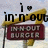 A pixelated sign with 'in-n-out' text above a maroon 'Burger' sign, featuring a black 'i' and heart symbol against a light background.